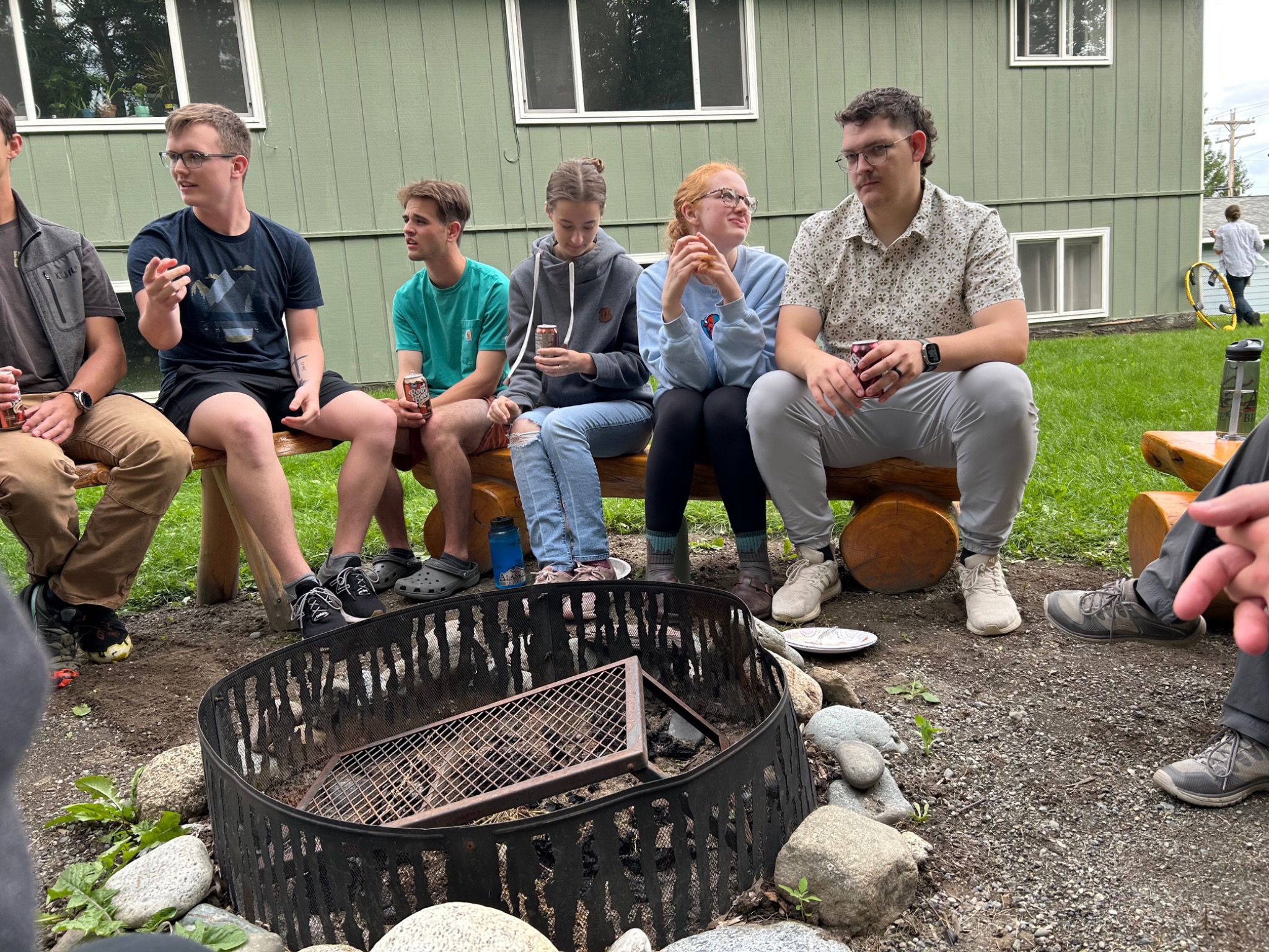 Students gathering around the firepit beside the ABC Quadplex
